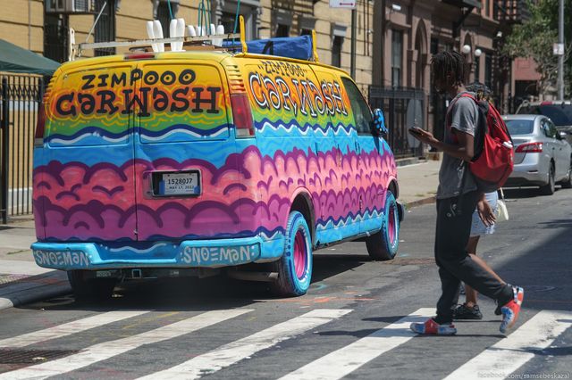 a young man walks past a colorful car wash van